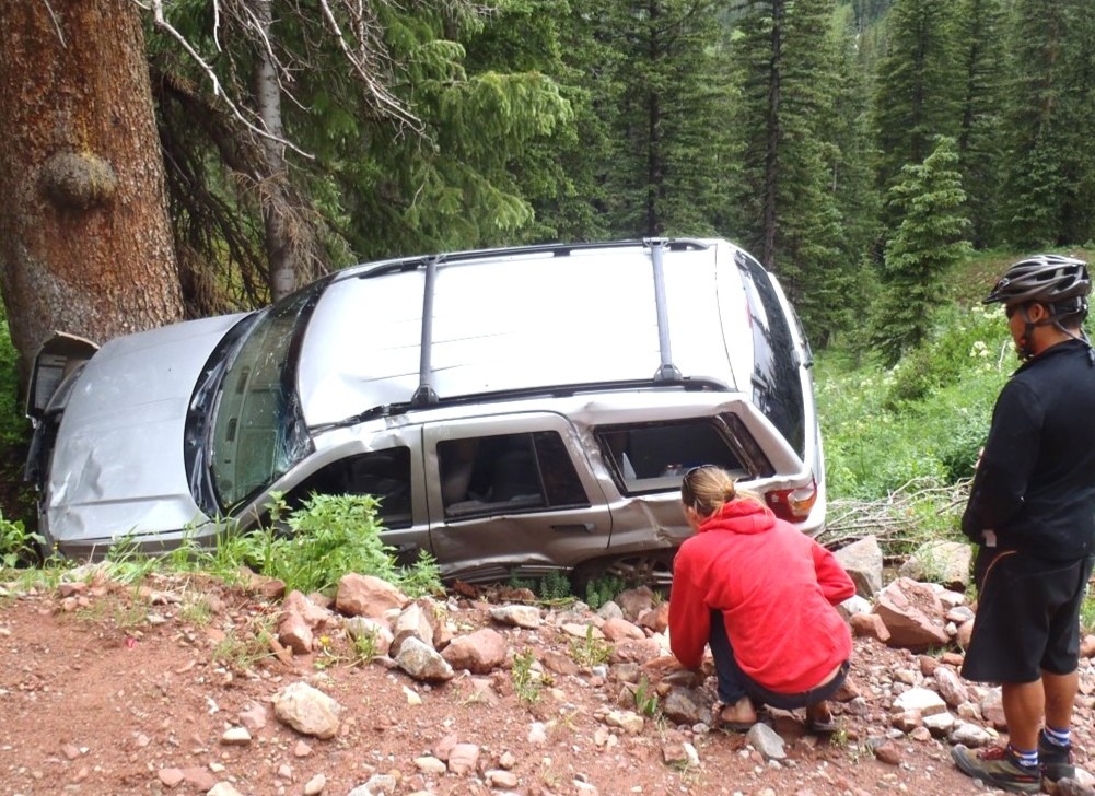 SUV lodged against a tree on a rugged mountain road